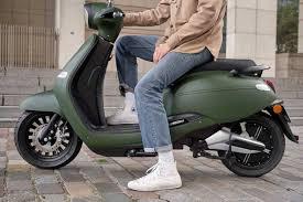 Un jeune homme sur un scooter vert armé
